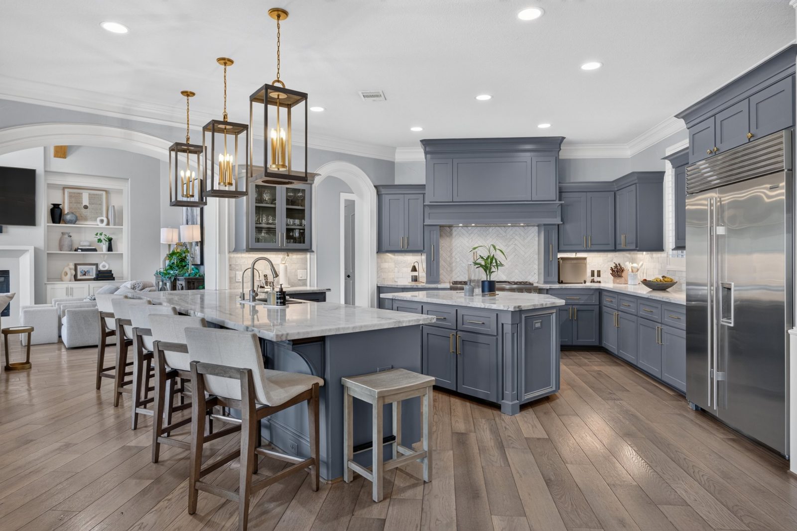 Kitchen with blue-gray cabinets, marble counters and brass lanterns