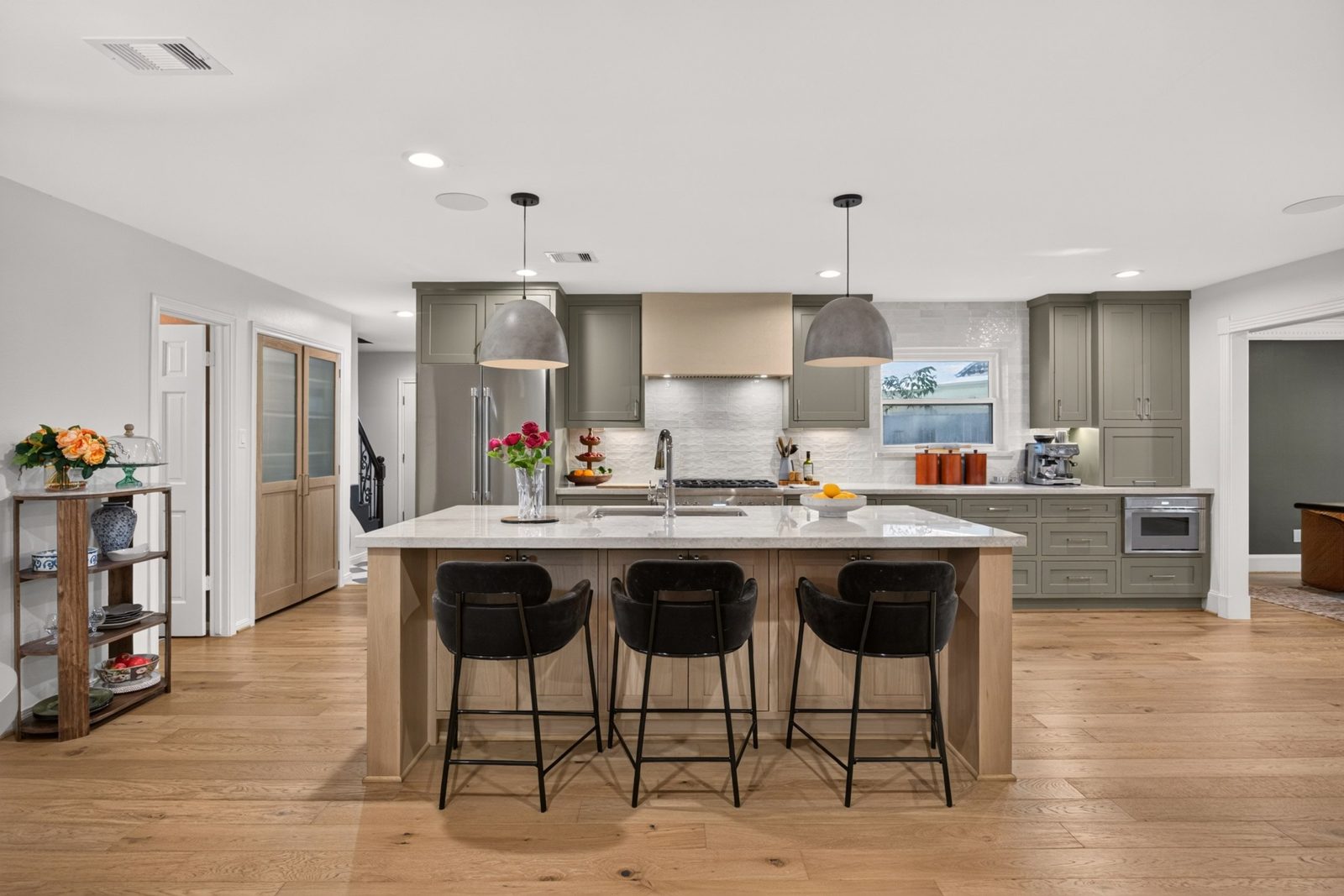 Bright open kitchen with a large island and three black bar stools